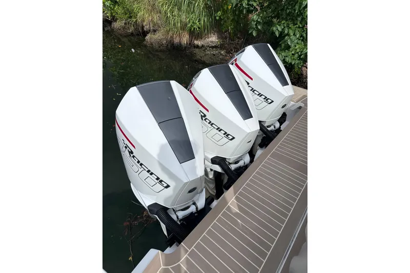 Slide: The Image of Triple outboard engines on 2024 Pardo Yachts P38, docked near lush greenery. - 40