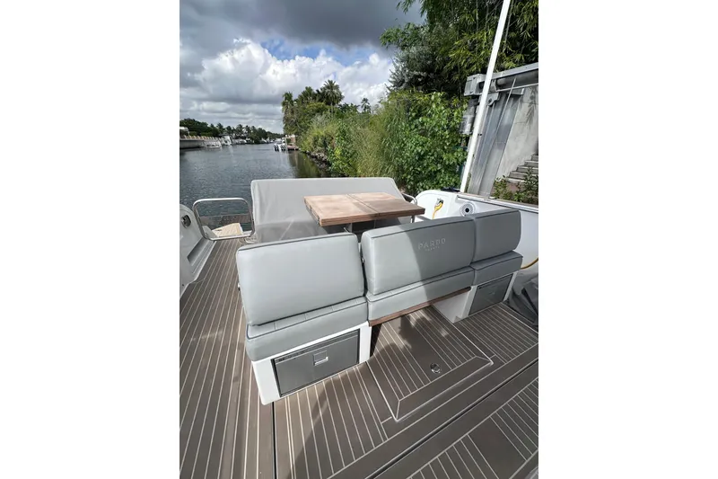 Slide: The Image of 2024 Pardo Yachts P38 deck with seating and table, docked by lush greenery. - 42