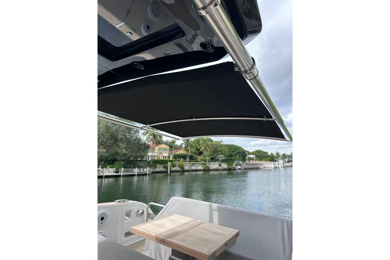 Slide: The Image of 2024 Pardo Yachts P38 with canopy, docked by a scenic waterfront. - 26