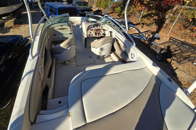 Slide: The Image of 2002 Sea Ray 220 Bow Rider interior with seating and steering wheel, parked outdoors. - 16