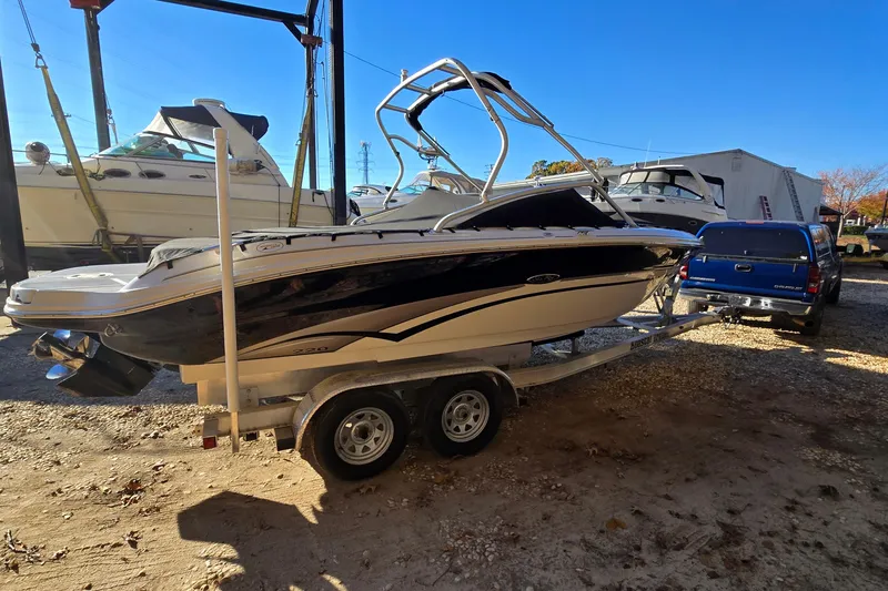 Slide: The Image of 2002 Sea Ray 220 Bow Rider on trailer, parked outdoors near other boats. - 2