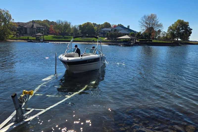 Slide: The Image of 2002 Sea Ray 220 Bow Rider on a serene lake near waterfront homes. - 29