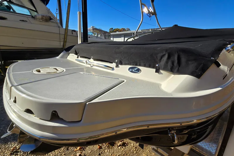Slide: The Image of 2002 Sea Ray 220 Bow Rider boat with black cover, docked under clear blue sky. - 4