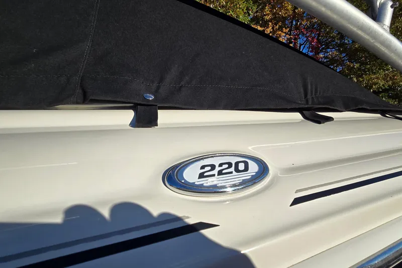 Slide: The Image of 2002 Sea Ray 220 Bow Rider boat with black cover and model emblem. - 6