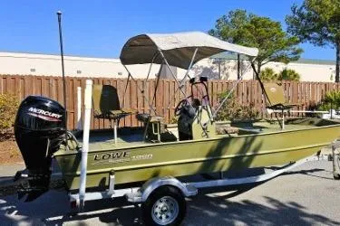 Slide: The Image of 2021 Lowe Roughneck 1860CC boat with camouflage seats, parked outdoors. - 2