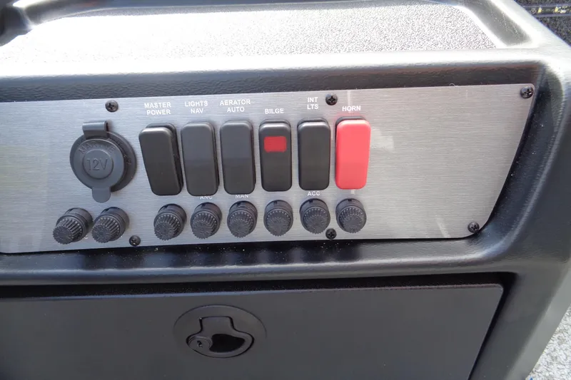 Slide: The Image of Control panel of 2026 Lund 1650 Angler Tiller boat with switches and 12V outlet. - 12