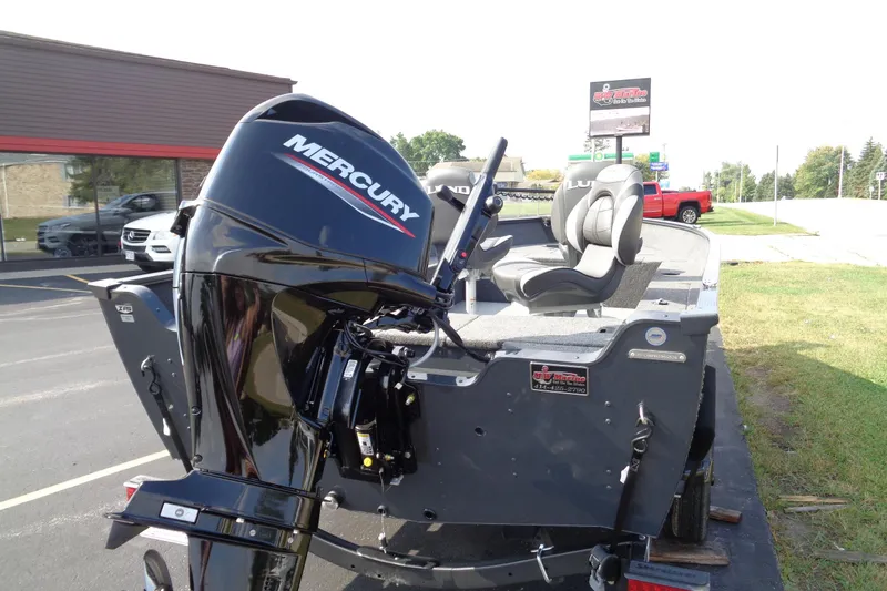 Slide: The Image of 2026 Lund 1650 Angler Tiller boat with Mercury engine, parked outdoors. - 5