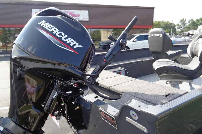 Slide: The Image of 2026 Lund 1650 Angler Tiller boat with Mercury outboard motor, parked outdoors. - 6