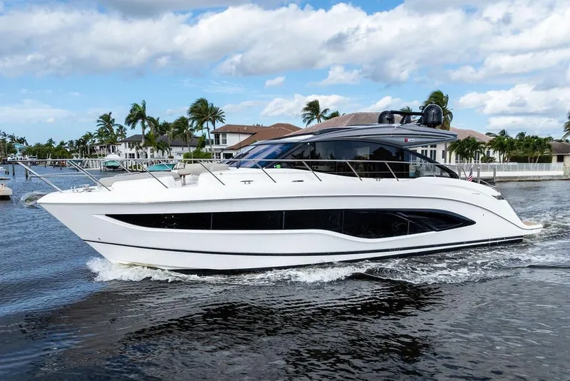 The Image of 2021 Princess V55 yacht cruising on a sunny day near waterfront homes. - 0