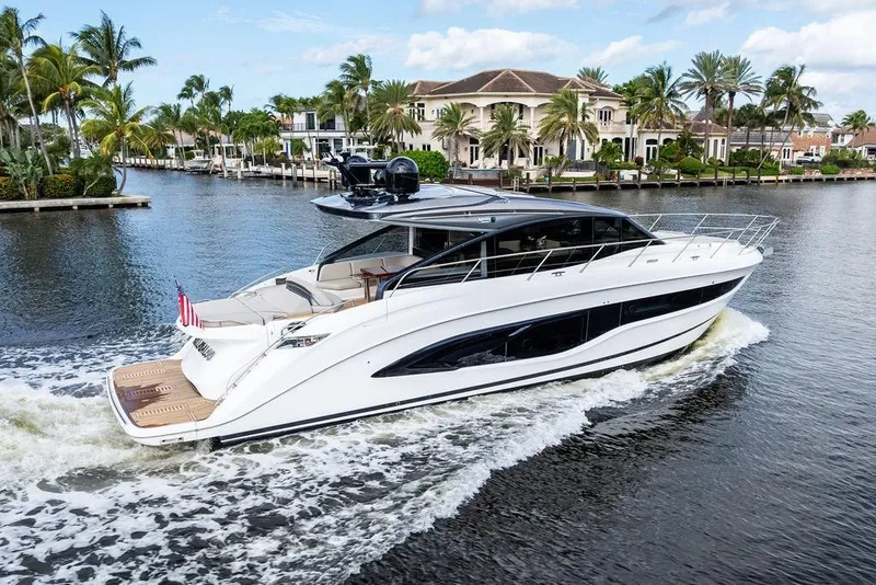 Slide: The Image of 2021 Princess V55 yacht cruising on a scenic waterway with luxury homes. - 1