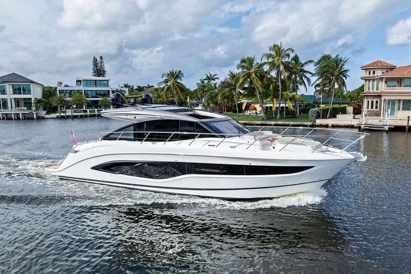 Slide: The Image of Luxury 2021 Princess V55 yacht cruising on a scenic waterway with palm trees. - 2