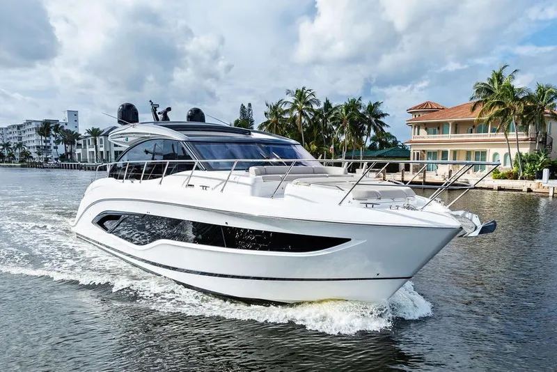 Slide: The Image of 2021 Princess V55 yacht cruising on a scenic waterway with palm trees and luxury homes. - 3
