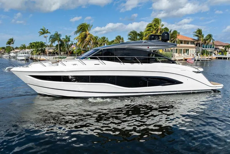 Slide: The Image of 2021 Princess V55 yacht cruising on a sunny day near waterfront homes. - 6