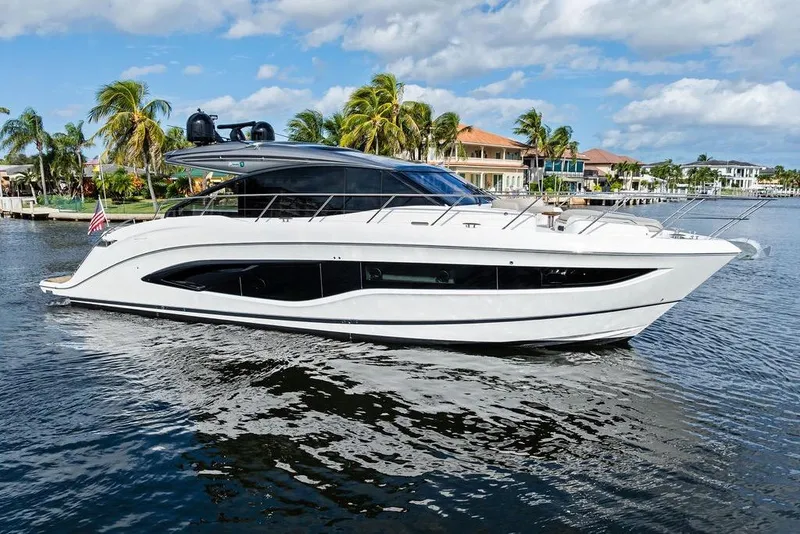 Slide: The Image of Luxury 2021 Princess V55 yacht cruising on a sunny day near waterfront homes. - 9