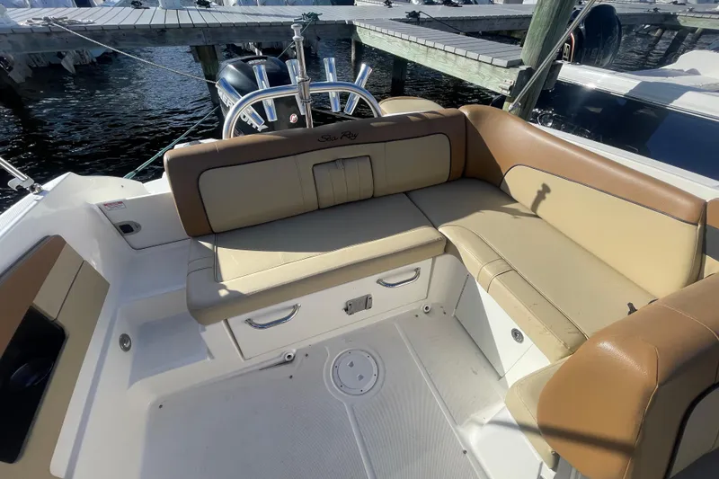 Slide: The Image of 2014 Sea Ray 240 Sundeck Outboard with tan seating, docked by the water. - 25