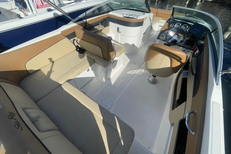 Slide: The Image of 2014 Sea Ray 240 Sundeck Outboard interior with tan seating and modern dashboard. - 26
