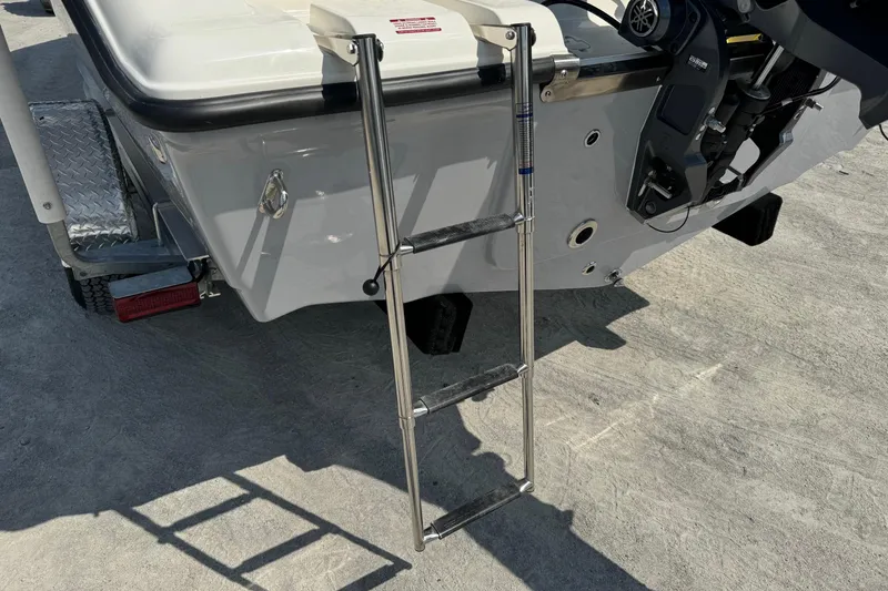 Slide: The Image of 2025 Key West 203 FS boat with stainless steel ladder and motor, parked on concrete. - 21