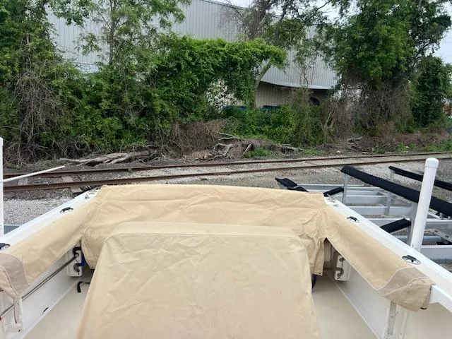 Slide: The Image of 2004 Hunt Yachts Surfhunter 25 with beige cover, near railway tracks and greenery. - 12