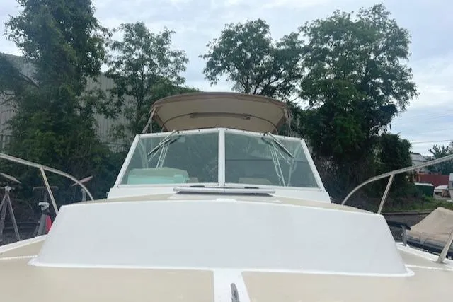 Slide: The Image of 2004 Hunt Yachts Surfhunter 25 with canopy, docked near trees. - 23