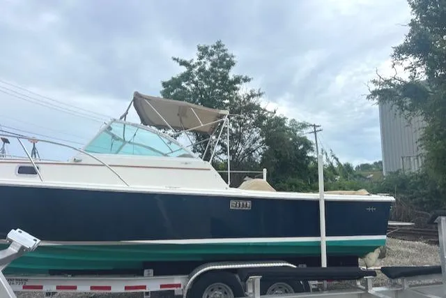 Slide: The Image of 2004 Hunt Yachts Surfhunter 25 on trailer, blue hull, canopy, overcast sky. - 5
