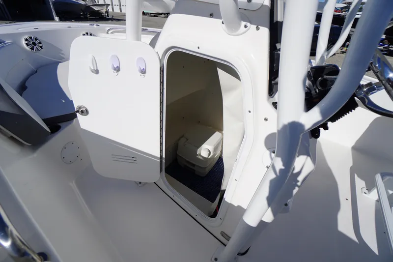 Slide: The Image of 2018 Tidewater 210 LXF boat interior with open storage compartment and portable toilet. - 12