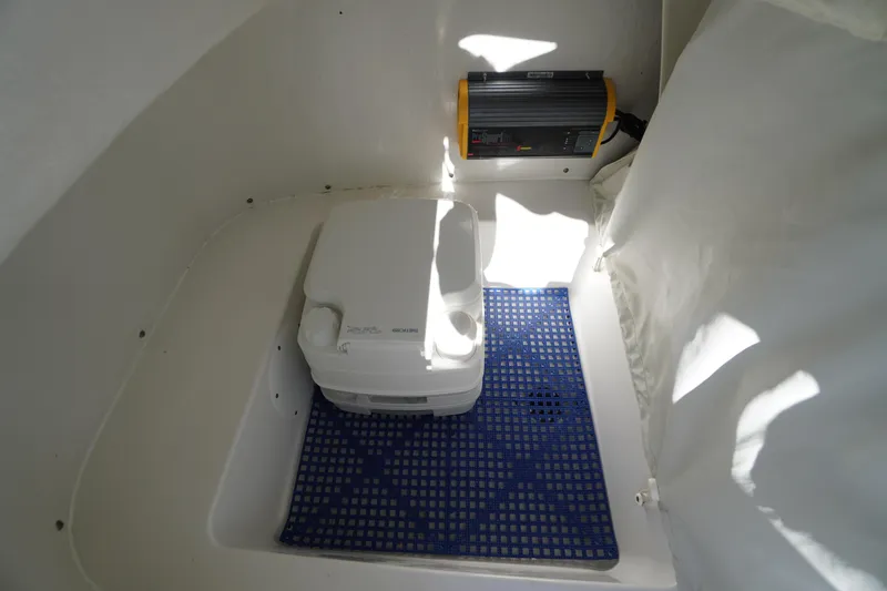 Slide: The Image of 2018 Tidewater 210 LXF boat interior with portable toilet and battery charger. - 13