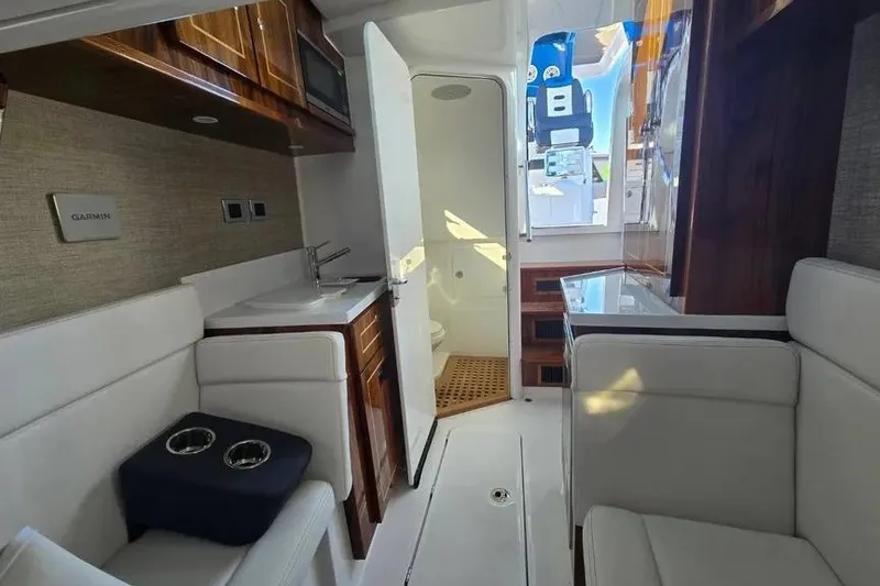 Slide: The Image of Interior of 2025 HCB 48 Campeon boat, featuring seating, sink, and restroom. - 18