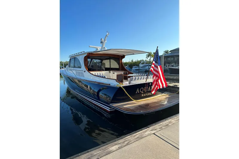 Slide: The Image of 2024 Hinckley Talaria 43 MY yacht docked, displaying American flag, sunny day. - 0