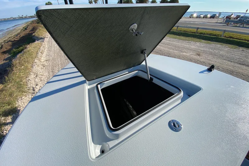 Slide: The Image of 2024 East Cape EVO 18V boat hatch open, showcasing storage compartment by the water. - 28