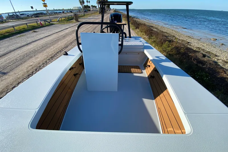 Slide: The Image of 2024 East Cape EVO 18V boat with sleek design, wooden accents, and coastal backdrop. - 30