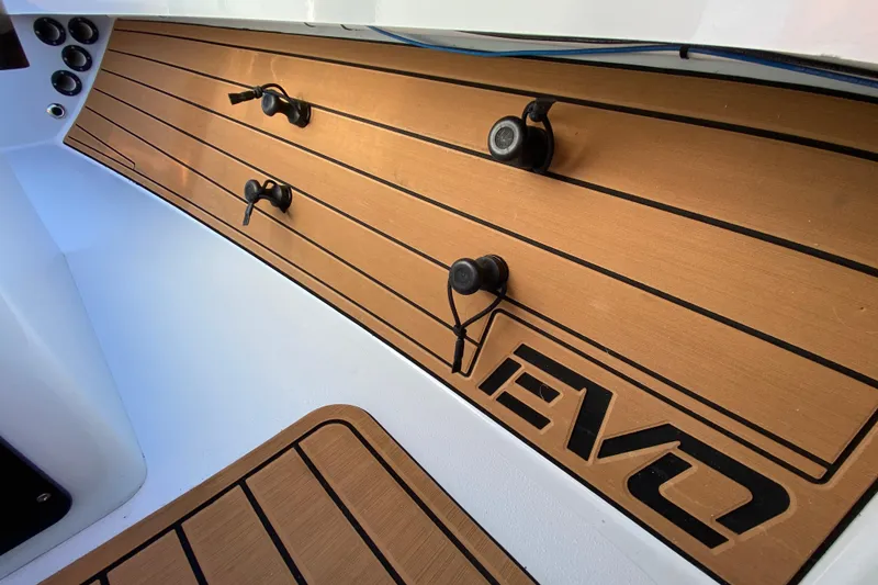 Slide: The Image of 2024 East Cape EVO 18V boat deck with wood finish and logo detail. - 34