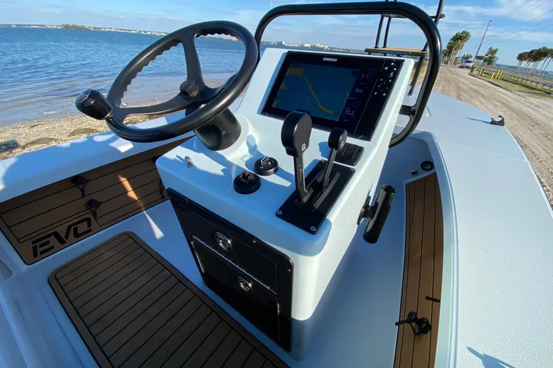 Slide: The Image of 2024 East Cape EVO 18V boat console with steering wheel and navigation display by the water. - 40