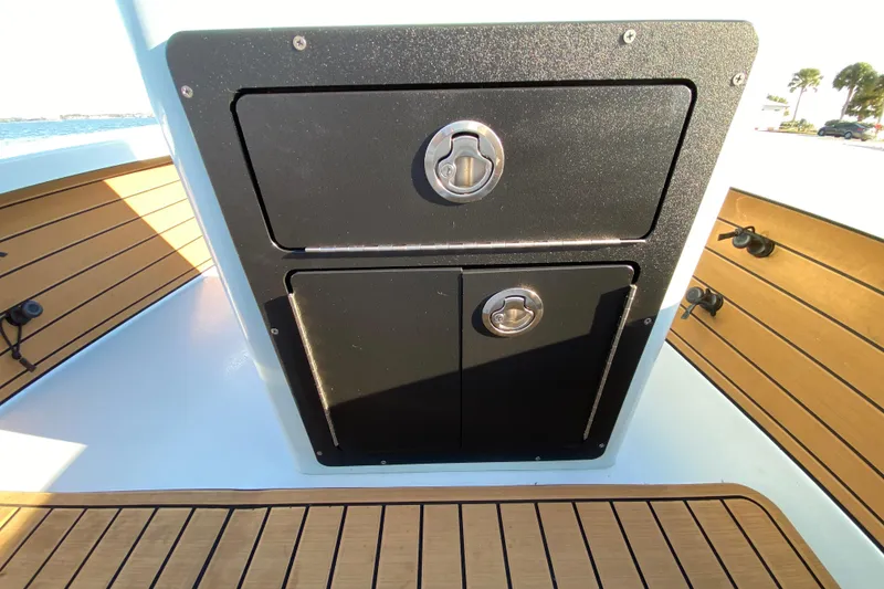 Slide: The Image of 2024 East Cape EVO 18V boat storage compartment with sleek black finish and wooden deck. - 43