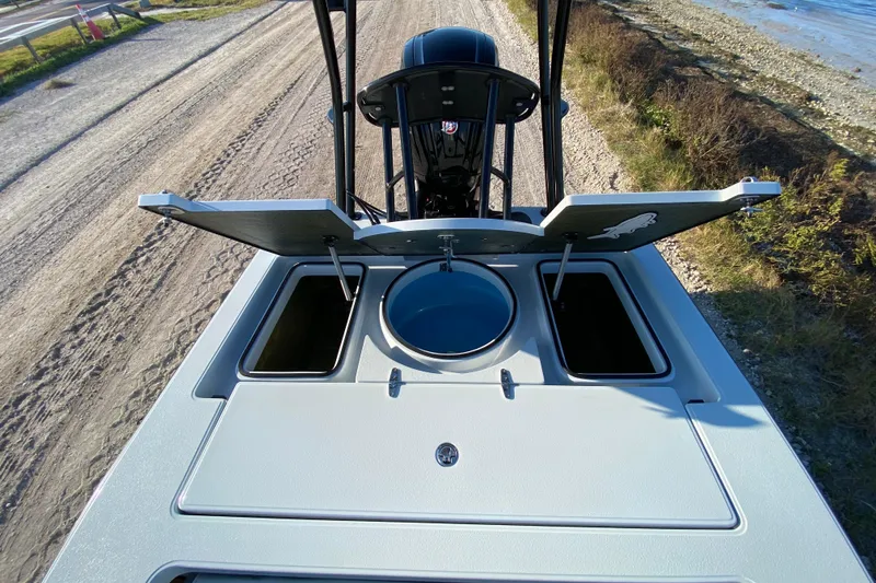 Slide: The Image of 2024 East Cape EVO 18V boat with open storage compartments and livewell, near a coastal road. - 48