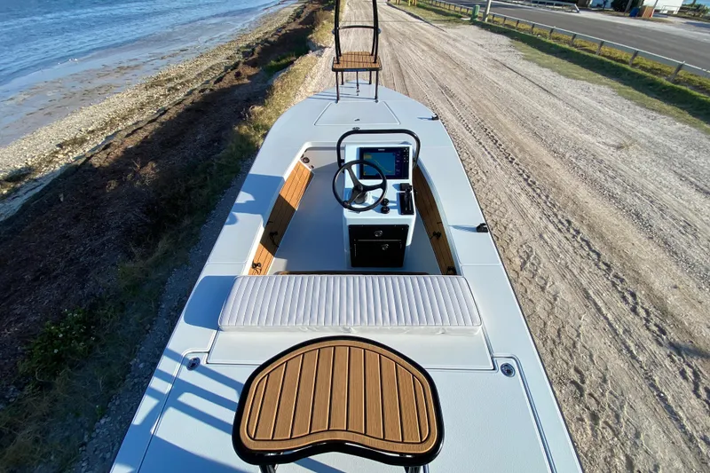 Slide: The Image of 2024 East Cape EVO 18V boat on sandy shore, featuring modern helm and seating. - 67