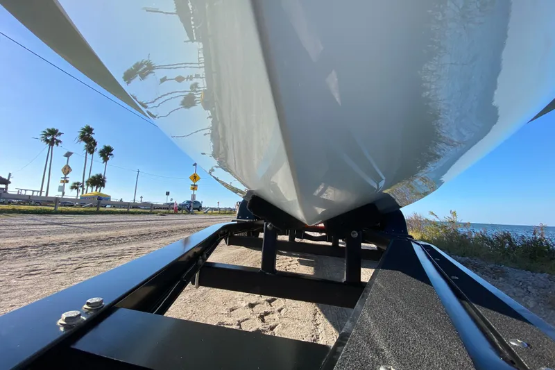 Slide: The Image of 2024 East Cape EVO 18V boat on trailer, coastal road, palm trees, clear sky. - 8