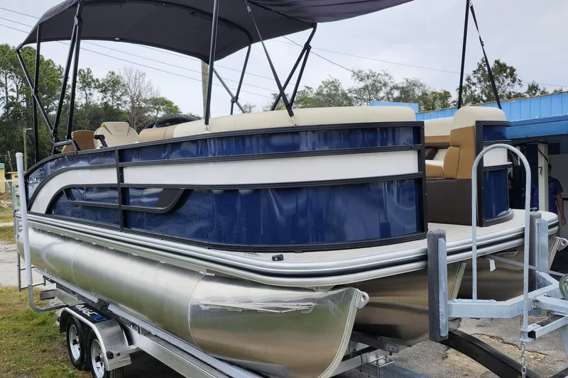 The Image of 2026 Lowe SF 212 Sport Fish pontoon boat on trailer, featuring blue and white design. - 1
