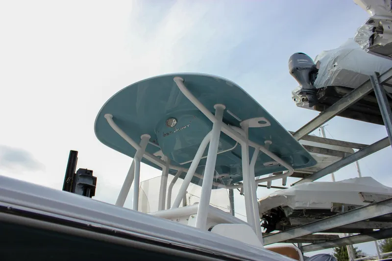 Slide: The Image of 2026 Sea Hunt Ultra 219 boat with blue T-top and Yamaha engine in storage. - 13