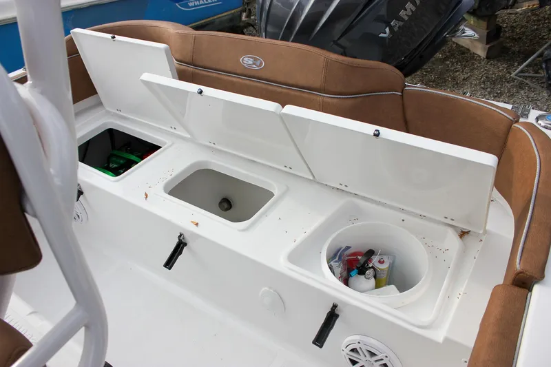Slide: The Image of 2026 Sea Hunt Ultra 219 boat storage compartments with brown seating and open hatches. - 26