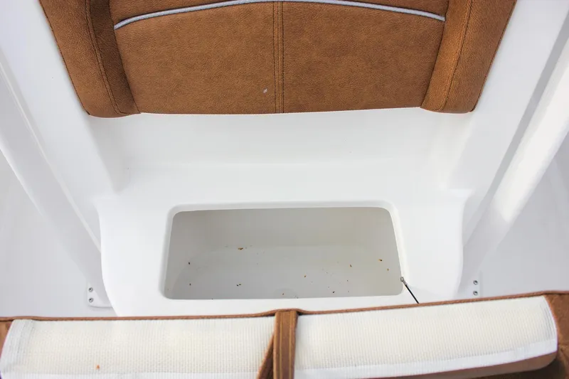 Slide: The Image of 2026 Sea Hunt Ultra 219 boat storage compartment with brown cushioned seating. - 40