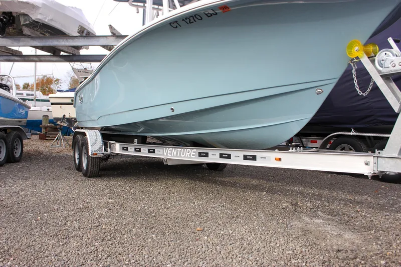 Slide: The Image of 2026 Sea Hunt Ultra 219 boat on a Venture trailer, parked on gravel. - 47