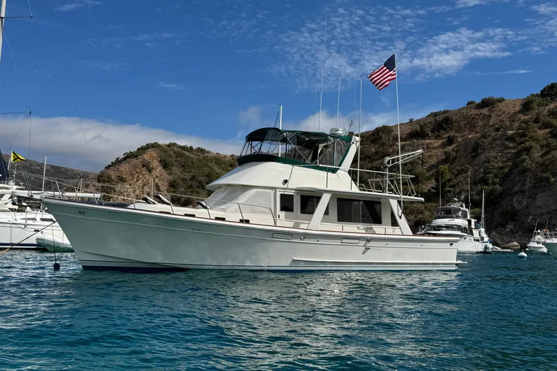 The Image of 1988 Offshore Yachts 48 Sedan anchored in scenic bay with American flag. - 0