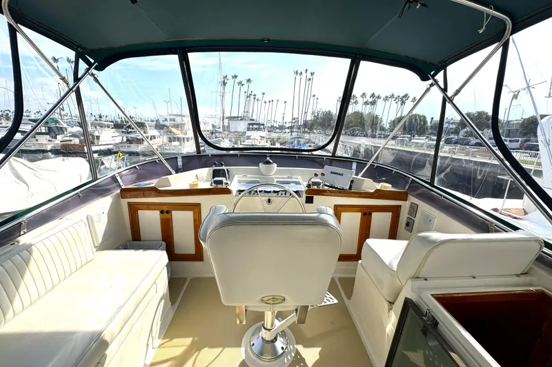 Slide: The Image of 1988 Offshore Yachts 48 Sedan interior with helm, seating, and marina view. - 15