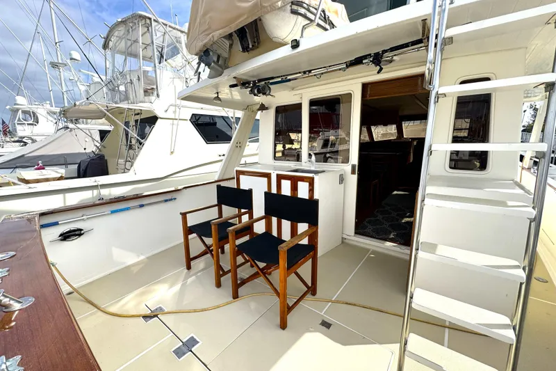 Slide: The Image of 1988 Offshore Yachts 48 Sedan deck with chairs and ladder, docked at marina. - 17