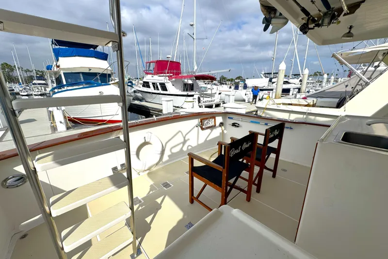Slide: The Image of 1988 Offshore Yachts 48 Sedan deck with chairs, ladder, and marina view. - 18