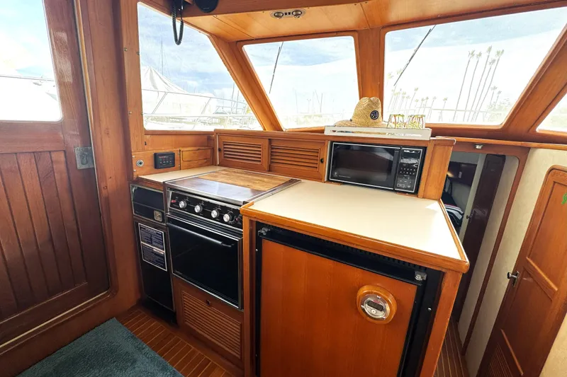 Slide: The Image of 1988 Offshore Yachts 48 Sedan kitchen with stove, microwave, and wooden cabinetry. - 8