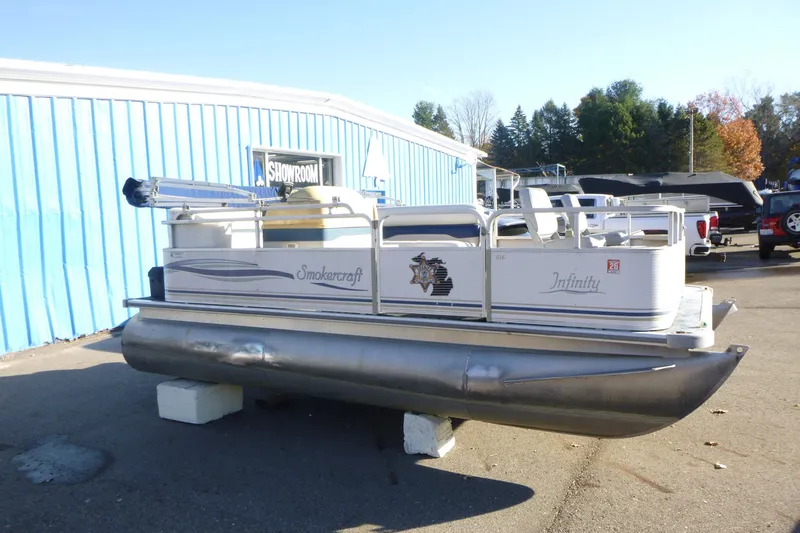 Slide: The Image of 2003 Smoker Craft 816 Infinity Fish pontoon boat displayed outside showroom. - 2