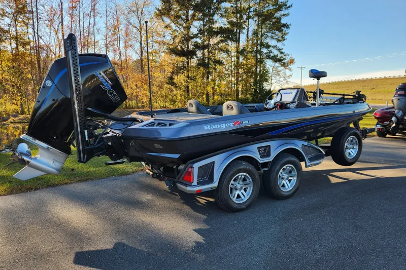 Slide: The Image of 2020 Ranger Z519 boat on trailer, parked outdoors with trees in background. - 2
