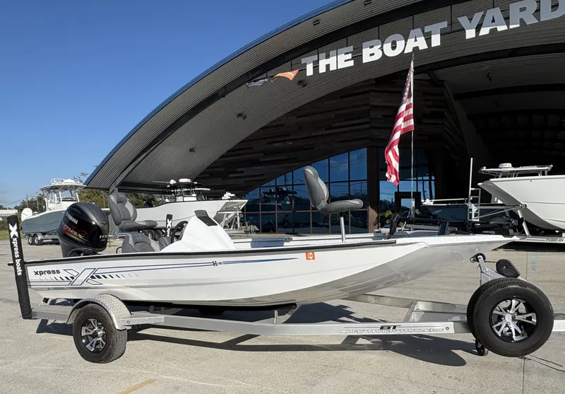 Slide: The Image of 2022 Xpress H18 boat on trailer, parked outdoors under clear blue sky. - 2