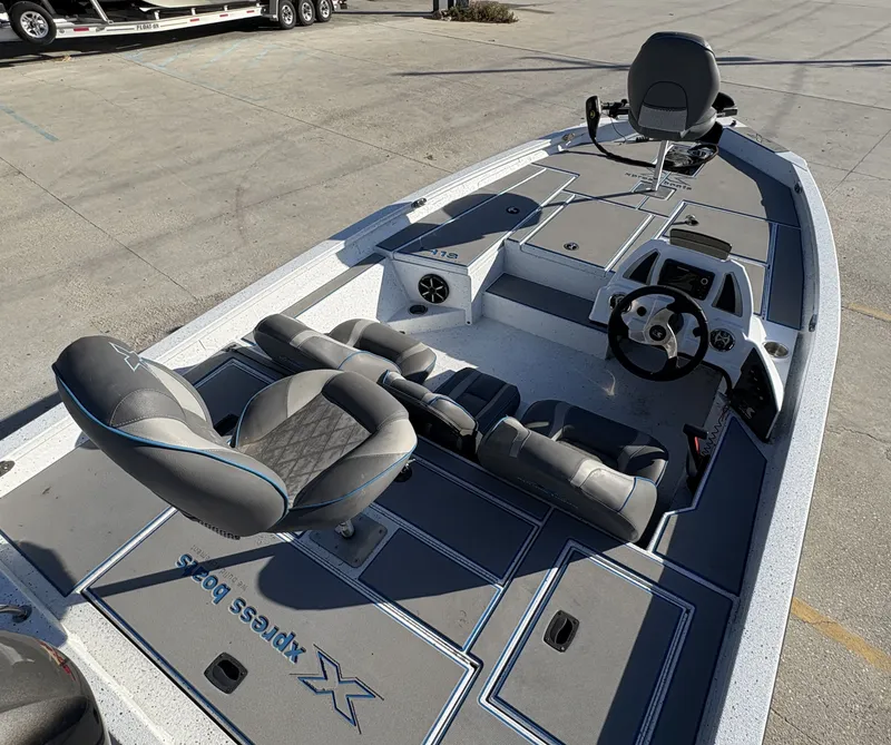 Slide: The Image of 2022 Xpress H18 boat interior with seating and steering wheel, parked on concrete. - 6